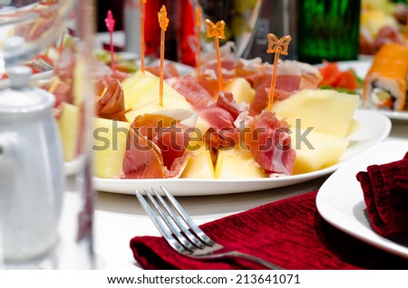 Serving of delicious smoked ham and cheese appetizers displayed on a plate on a buffet at a party or reception