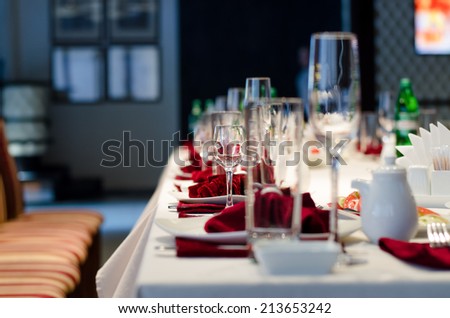 Formal stylish setting on a dinner table with elegant glassware and red linen for a party or celebration of a special event