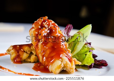 Close up Gourmet Mouth Watering Crispy Fried Chicken with Sweet Sauce and Sesame Seeds and Veggies on White Plate.