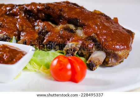 Close Up of Rack of Saucy Barbecue Pork Ribs Served on Plate in Restaurant