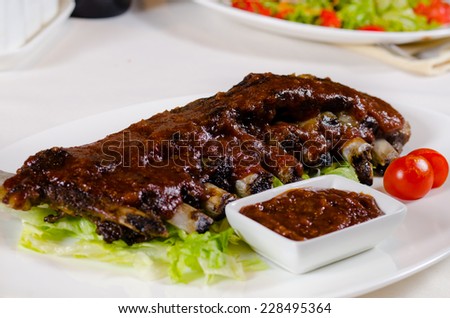 Rack of Saucy Barbecue Pork Ribs on White Plate Served in Restaurant