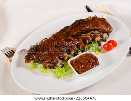 Rack of Saucy Barbecue Pork Ribs on White Plate Served in Restaurant