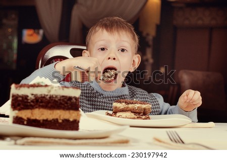 Open wide - a little boy opens his mouth wide to take a large mouthful of a delicious freshly baked slice of cake for dessert