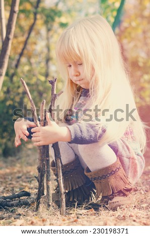 Close up Cute Little Blond Girl Playing with Dry Sticks on the Ground at the Forest. Captured During Autumn Season.