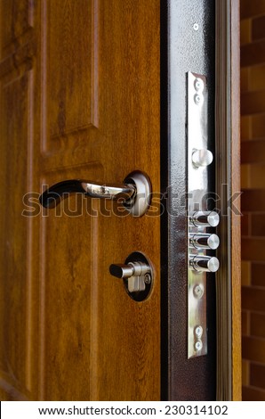 Triple cylinders on a new high security lock installed in a wooden front door to a home with the locks extended