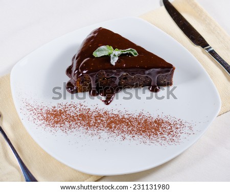 High angle view of a slice of freshly baked chocolate tart with rich chocolate sauce dripping down the sides served on a plate for dessert