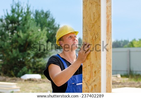 Builder installing wall insulation holding upright a wooden insulated polystyrene beam in a vertical position on a building site