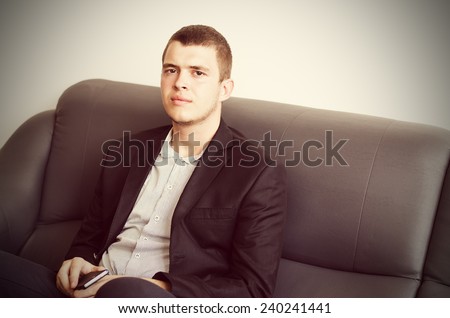 Close up Sitting Gorgeous Young Man in Black Corporate Coat Looking at Camera While