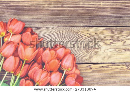 Bouquet of delicate fresh red tulips lying on a wood textured background with wood grain pattern and copyspace for a Valentines Day card