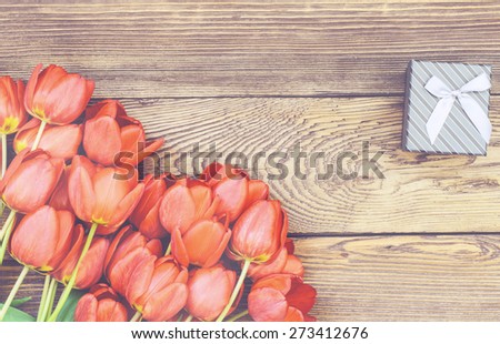 Bouquet of fresh colorful red tulips with a decorative gift lying on a rustic wooden background symbolic of an anniversary, Valentines Day and love, overhead view