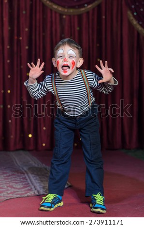 Boy Wearing Clown Make Up, Striped Shirt and Suspenders Making Face and Hand Gestures on Stage Towards Camera