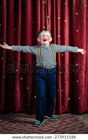 Young Boy Dressed as Clown Performing on Stage with Open Arms and Open Mouth as if Singing or Acting