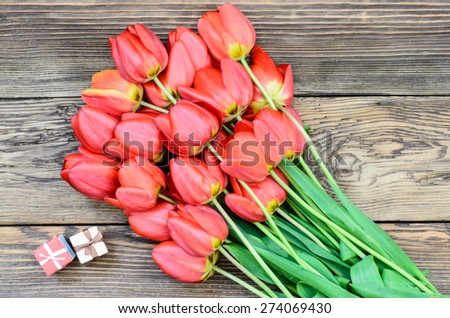 Bouquet of Fresh Orange Tulip Flowers on Top of Wooden Table with Gift Boxes, Captured in High Angle View.