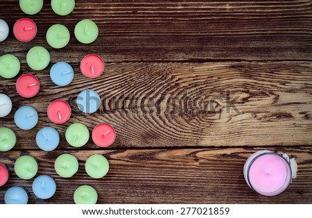 High Angle View of Colorful Unlit Tealight Candles with One Larger Purple Colored Candle Arranged to One Side with Copy Space on Wooden Background