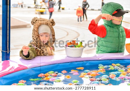 Children Wearing Warm Clothing Playing at Fishing Pond Amusement Game at Outdoor Fun Fair Carnival