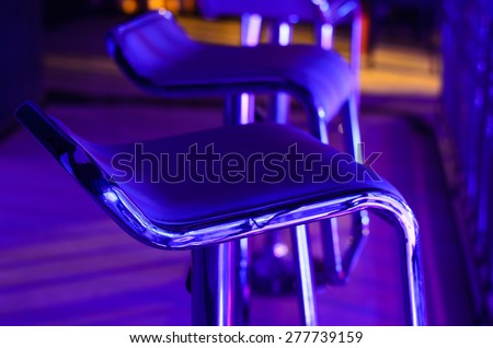 Detail of Empty Bar Stool Lit in Purple Blue Light at Night Club or Bar