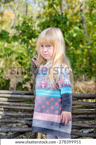 Young Serious Looking Blond Girl Climbing Stile Over Rustic Wooden Fence in Rural Wooded Area
