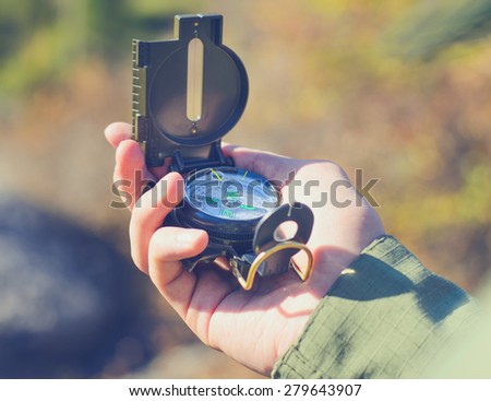 Close up Man Hand Holding Compass Device to Find Direction at the Camping Area.