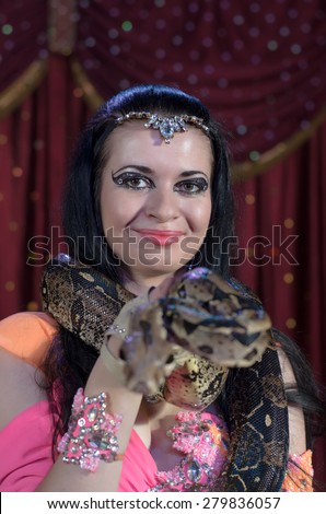 Portrait of Dark Haired Exotic Snake Charmer Female Dancer with Large Snake Around Neck Smiling at Camera