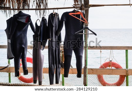 Scuba Diving Wet Suits Hanging to Dry on Rail on Deck of Boat with View of Ocean in Background