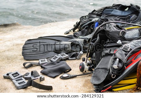 Pile of Scuba Diving Equipment Including Fins and Weights Drying on Coastal Dock near Water