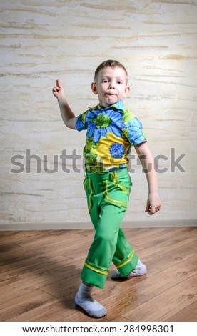 Young Boy Wearing Green Pants and Floral Print Shirt Snapping Fingers and Performing Traditional Dance in Studio