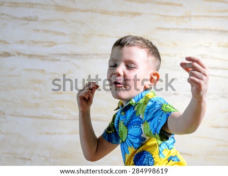 Head and Shoulders Close Up of Young Boy Singing and Dancing and Snapping Fingers with Eyes Closed in Studio with Patterned Background, Looks Joyful and Happy