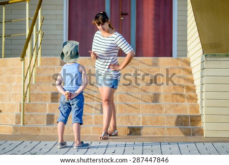 Angry Mother Scolding Son in front of Home - Young Boy Hiding Ice Cream Cone Behind Back and Getting into Trouble