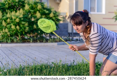 Young Woman Crawling on Lawn with Bug Net Searching for Something in front of Home