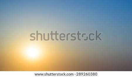 Fiery orange sunset with the glowing orb of the sun in a clear deep blue twilight sky, weather and nature background