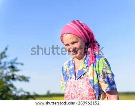 Close up Senior Female Farmer at the Green Fields, with Cloth Cover on her Head, Showing Happy Facial Expression on One Sunny Day.