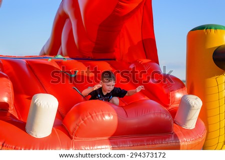 Small boy (6-8 years) wearing black t-shirt plays in red bouncy castle
