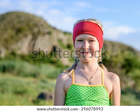 Close up Cute Girl in Casual Sleeveless Tops with Red Headband Smiling at the Camera Against the Cliff.