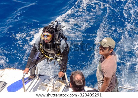 Sharm El Sheikh, Egypt - 29 Jule 2015:Scuba diver in his gear on a dive boat standing ready to enter the water from the back of the boat, high angle view with the wake of the moving boat behind
