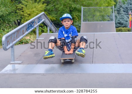 Excited little boy trying out his new skateboard at the skate park riding down a ramp balanced on his hands