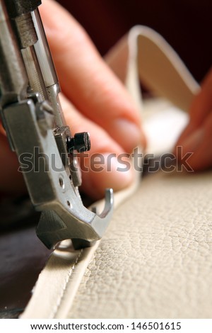 sewing machine in action for working leather for a sofa
