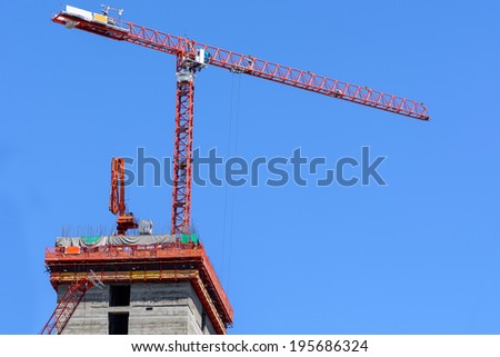 Building under construction site with red crane ,	engineer works site ,blue sky background