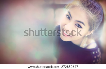 Asian woman  Smile and looking camera bird\'s-eye view with Bokeh teenager gold-brown hair ,make up eye-liner and other ,wearing black T-shirt ,expression so friendly ,bokeh blank for text