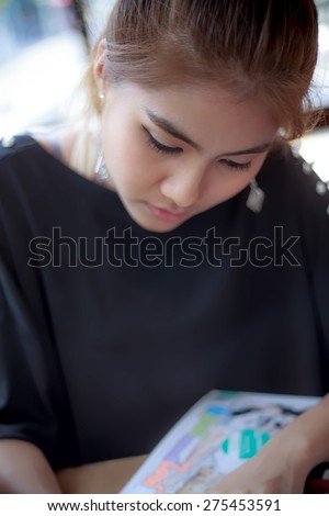 woman Asia happy clam sitting for reading magazine Black shirts Note to editor:teenager gold-brown hair ,make up eye-liner and other ,wearing black T-shirt