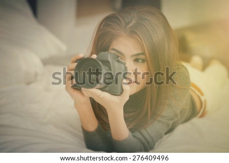 Asian woman hold dslr black camera with Light Fair old style on white bed look vintage style long gray shirt so lovely girl