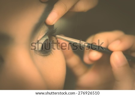 Close up macro lens depth of field show fingers Hands of woman  with contact lens brown eyes Make up eye with black brush,look film camera behind the scenes style