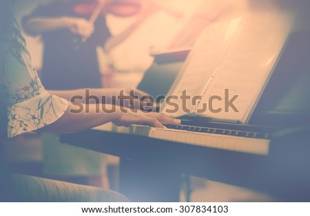 Vintage style Hands woman playing piano with light behind woman playing violin