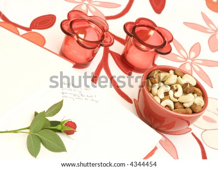 Book, rose, candles and a bowl of mixed nuts. The book have an inscription with birthday wishes