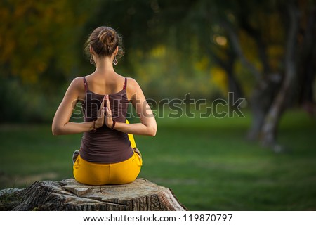 Young woman doing yoga exercises in the autumn city park.