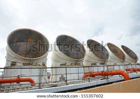 Exhaust vents of industrial air conditioning and ventilation units on the roof top of large building.