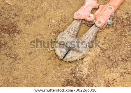 Rusty heavy metal cutting pliers on the sand ground