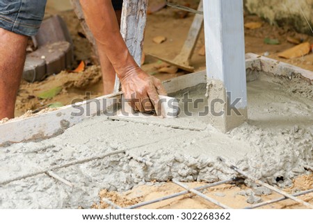 Construction worker using trowel to finish wet concrete floor