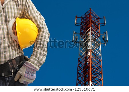 technician against telecommunication tower, painted white and red in a day of clear blue sky.