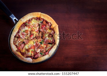 delicious pizza in pan on wooden background