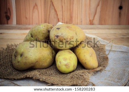 fresh harvested potatoes on a burlap bag, on a rough wooden palette